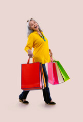 An old woman happily holding colorful carrybags.