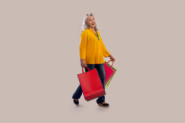 An old woman happily holding colorful carrybags.