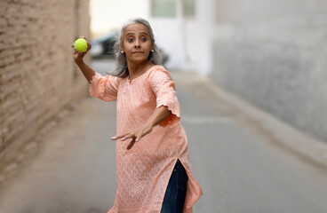An old woman playing cricket Bowling.