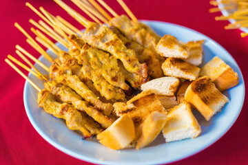 Grilled pork Satay is served with toast,peanut sauce,pickles which are cucumber and onion sliced in vinegar.