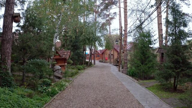 Beautiful small village with brick cottages located in ecological place. Video. Following the gravel path along growing trees and houses on a summer day.