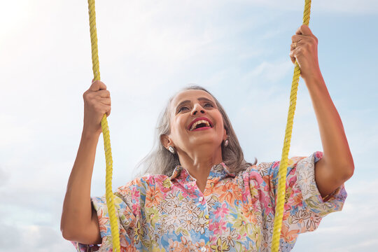 An Old Woman Swinging With Two Ropes In Her Hands.