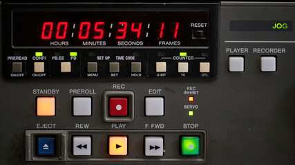 Close up of the control panel and timecode display of an old broadcast tape recorder where we can see the playback buttons and the timecode running