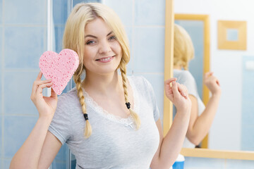 Blonde woman in braids holding heart