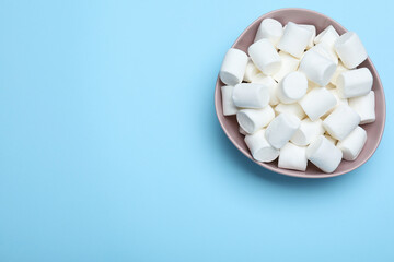 Delicious puffy marshmallows on light blue background, top view. Space for text
