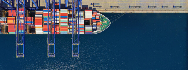 Aerial top down ultra wide photo of industrial container ship loading  - unloading colourful truck...