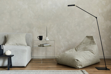 Creative composition of stylish modern spacious living room with pouf, sofa, glass coffee table,...