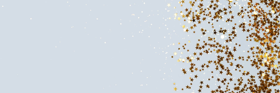Banner with bright gold glittering stars confetti scattered on a blue pastel background with place for text.