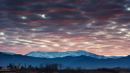 Beautiful colored sunset with mountain covered in snow in late Winter