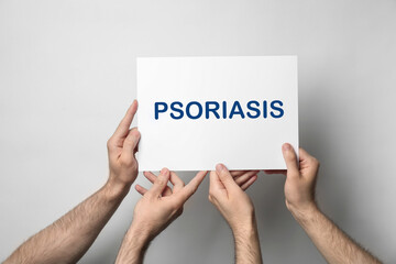 Men holding card with word PSORIASIS on light background, closeup