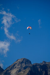 Paraplaners in tandem gliding in blue sky and Alpine mountains on paraplane