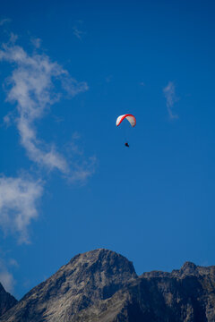 Paraplaners in tandem gliding in blue sky and Alpine mountains on paraplane