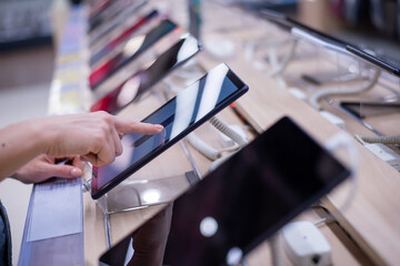 Faceless caucasian woman chooses a smartphone in an electronics store. Close-up of a female hand with a phone tester