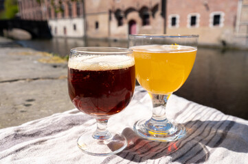 Tasting of Belgian beer on open cafe or bistro terrace with view on medieval houses and canals in Bruges, Belgium