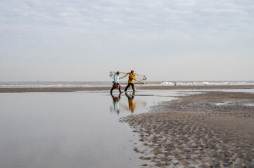 27 April 2021, De Haan, Belgium, two fishermans collect mussels clams during low tide on sandy beach