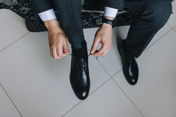 A man, a businessman ties long shoelaces on leather black shoes with his hands in a jacket...