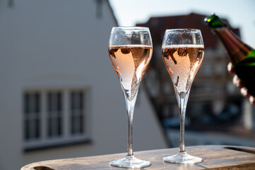 Drinking of rose champagne sparkling wine from flute glasses on outdoor terrace in France