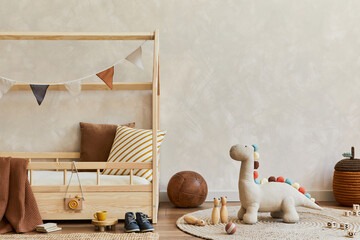 Stylish composition of cozy scandinavian child's room interior with creative wooden bed, plush and wooden toys and textile hanging decorations. Neutral creative wall. Copy space. Template. .