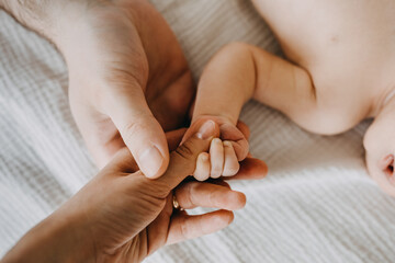 Father and mother holding small newborn baby hand, closeup. - obrazy, fototapety, plakaty