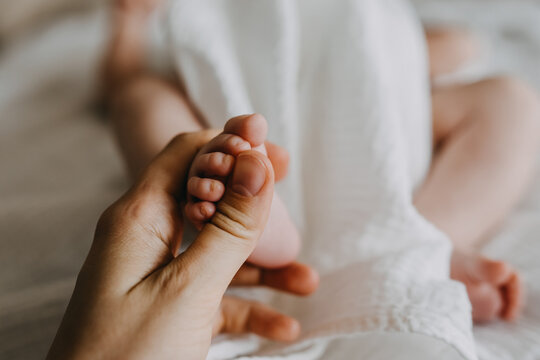 Closeup of mother holding small newborn baby foot.