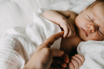 Closeup of a newborn baby holding mother's finger. - obrazy, fototapety, plakaty