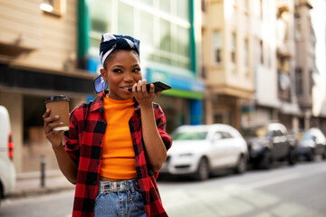 Happy african woman using the phone while drinking coffee. Beautiful woman talking to the phone