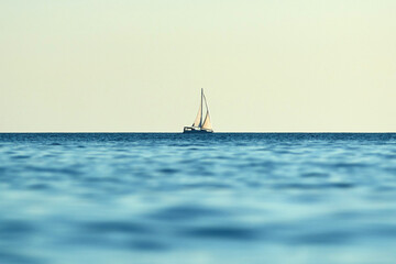 Sailing boat and blue ocean water with horizon.