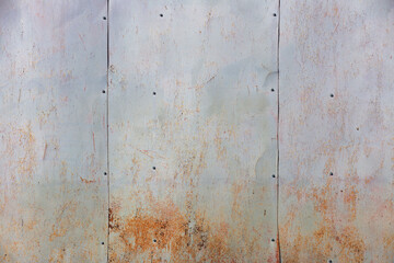 old sheets of iron on the wall of the house with remnants of paint and rust, background, texture