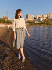 Woman in dress enjoys the sea shore.