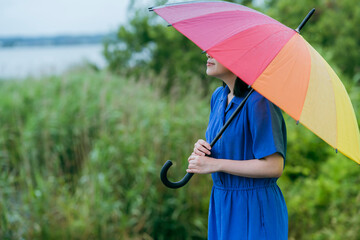 雨の中、カラフルな傘を指す女性