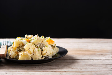 Potato salad with gherkins, egg and mustard on wooden table. Copy space
