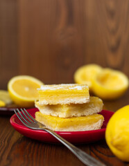 side view of juicy yellow lemon cakes on wooden background, stack of citrus cookies with lemon filling lying one on top of another