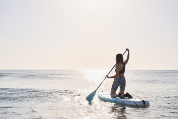 Girl paddling on a paddle board at sunrise