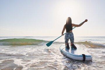 Fototapeta na wymiar Girl paddling on a paddle board at sunrise