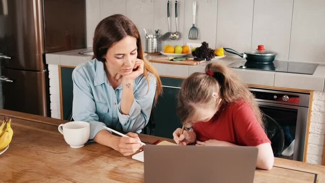 A young girl with down syndrome is doing lessons with her mother at home