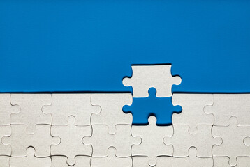 White jigsaw puzzle pieces. Fill in pieces of the jigsaw puzzle. Complete the jigsaw puzzle with the missing pieces. Fragment of a folded white jigsaw puzzle.