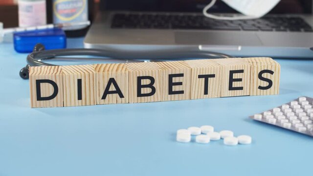 Wooden cubes with inscription diabetes are placed by doctor on table. Appearing cubes with the word diabetes complement the medical table full of medicines
