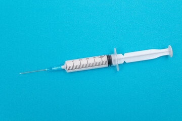 A Syringe with White Liquid Inside on Blue Table. Disposable Plastic Syringe is Prepared for...