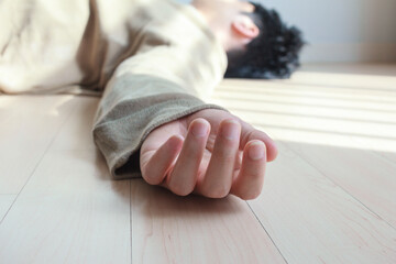 Close up photo of man's hand lying on the floor.