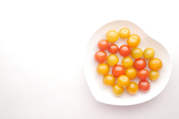 color cherry tomato on heart shape plate on white background 