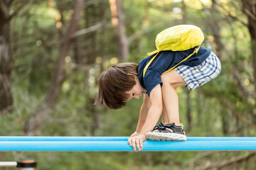 Little boy having fun playing on equipment in park