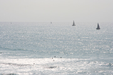 Calm sea with sunset sky and sun with windsurfer silhouettes over sea sunset, panoramic beach landscape, summertime fun, sport, activities, vacation and travel concept.