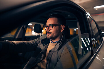 Attractive guy driving car at night - Powered by Adobe