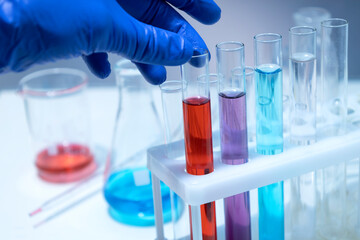 Closeup of laboratory assistant hand wearing blue gloves and holding glass tube of lab liquid.Concept of laboratory testing