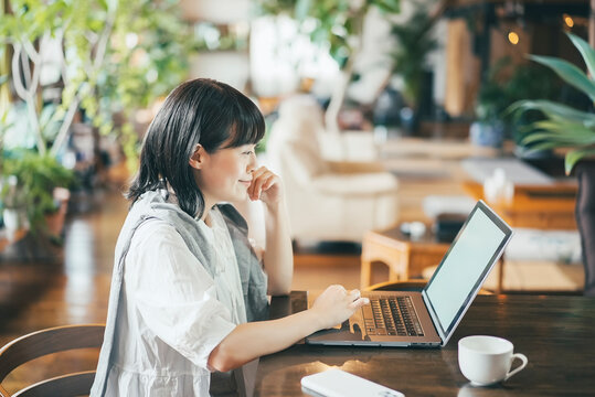 暖かい雰囲気の空間で、ノートパソコンの画面を見る女性