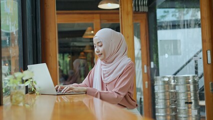 Young muslim woman use laptop for working in coffee shop