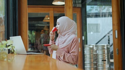 Fototapeta na wymiar Young muslim woman drink hot coffee in cafe