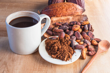 Hot cocoa cup with cocoa powder and cocoa beans on wooden background