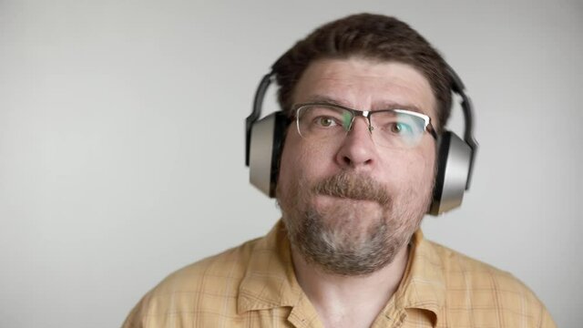Portrait of bearded 48 years old caucasian man enjoy listen to romantic slow music by wireless silver headphones at home.