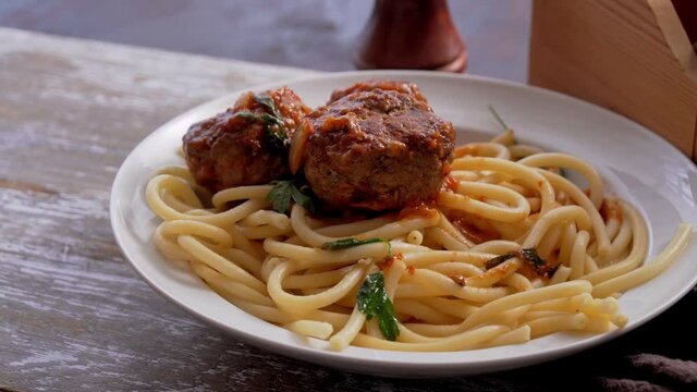 Spaghetti with meatball and parsley on table